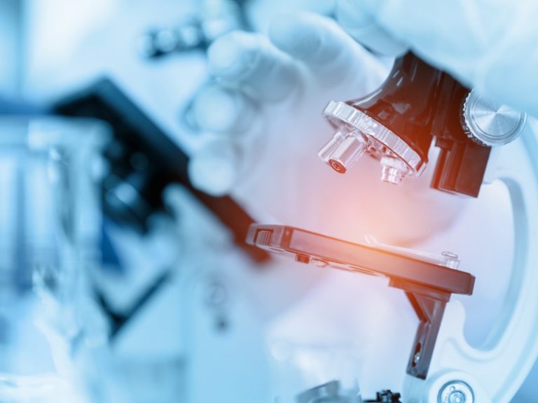 Close Up Scientist using microscope in laboratory room